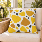 Yellow terrazzo outdoor pillow on a rattan chair on a sunny summer porch