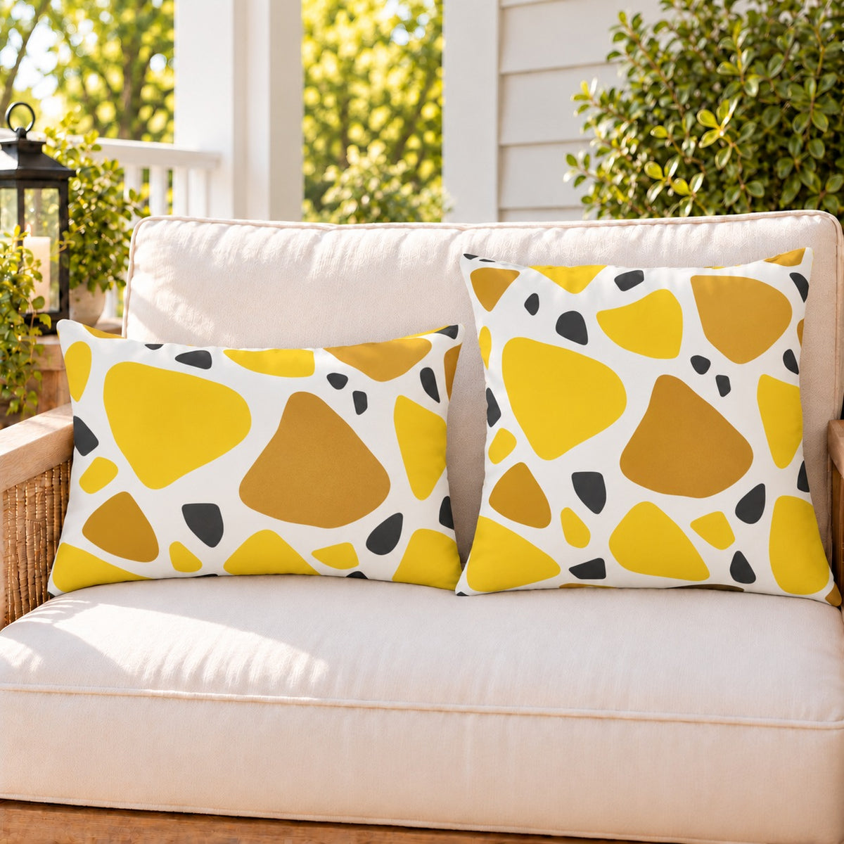 Yellow terrazzo outdoor pillow and outdoor lumbar pillow styled together as a set on a porch loveseat